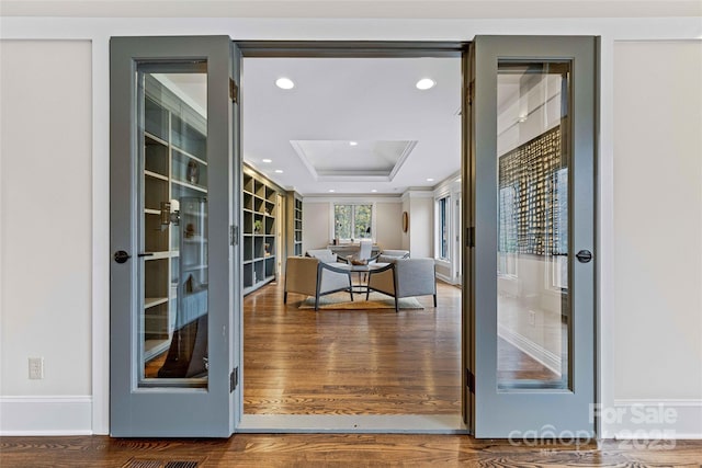 doorway to outside featuring a tray ceiling, recessed lighting, and wood finished floors