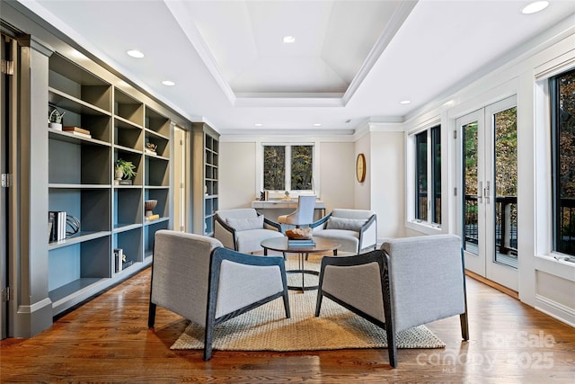 sitting room with ornamental molding, a tray ceiling, wood finished floors, and recessed lighting