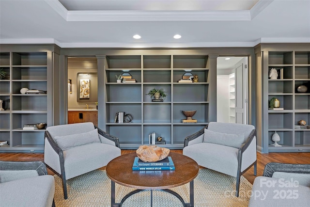 living area with ornamental molding, recessed lighting, a tray ceiling, and wood finished floors