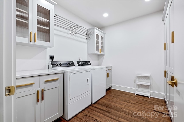 washroom featuring recessed lighting, dark wood-type flooring, baseboards, cabinet space, and washer and clothes dryer