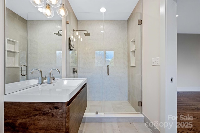 bathroom featuring a stall shower, baseboards, and a sink