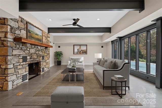 living room featuring ceiling fan, baseboards, beamed ceiling, and a stone fireplace