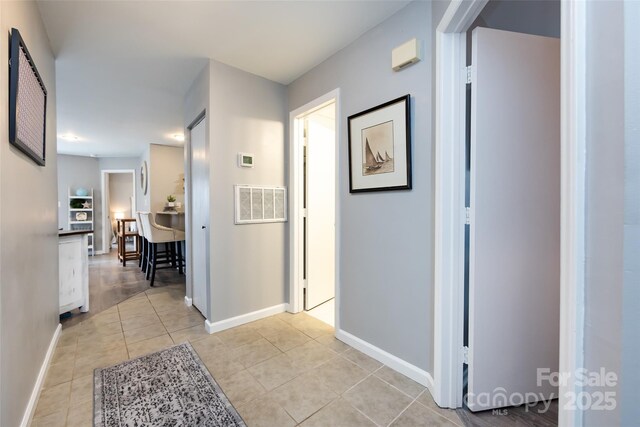 corridor featuring light tile patterned floors, visible vents, and baseboards