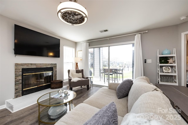 living room featuring a glass covered fireplace, wood finished floors, and visible vents