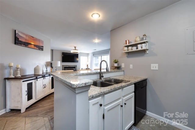 kitchen featuring a fireplace, open floor plan, a sink, dishwasher, and a peninsula