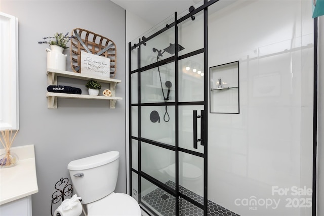 full bath featuring a stall shower, vanity, and toilet