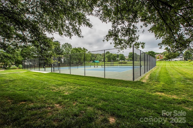 view of tennis court featuring a yard and fence