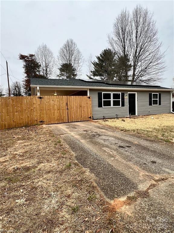 ranch-style home featuring driveway and fence