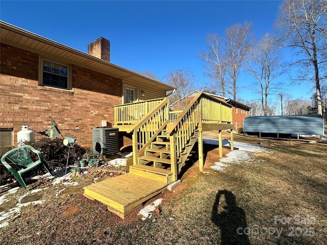 exterior space featuring a chimney, stairway, cooling unit, a wooden deck, and brick siding