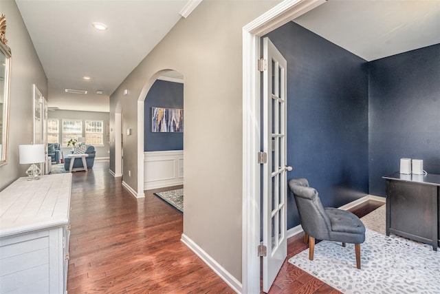 corridor featuring arched walkways, recessed lighting, visible vents, wood finished floors, and baseboards