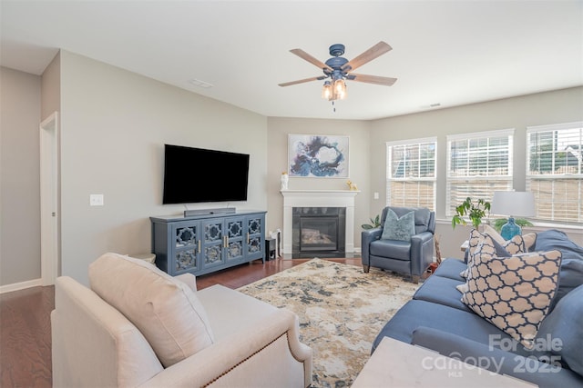 living room featuring ceiling fan, a fireplace, wood finished floors, and baseboards