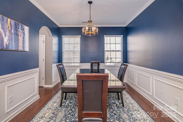 dining area featuring dark wood-style floors, arched walkways, wainscoting, and an inviting chandelier