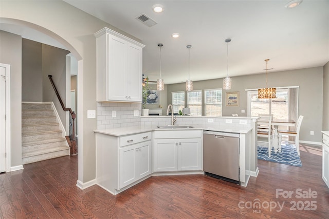 kitchen featuring visible vents, a peninsula, light countertops, stainless steel dishwasher, and a sink