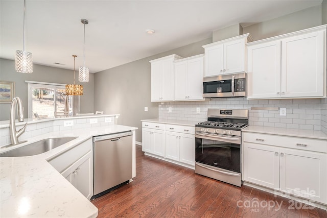 kitchen with stainless steel appliances, dark wood-style flooring, a sink, white cabinetry, and backsplash