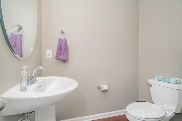 bathroom with toilet, baseboards, a sink, and wood finished floors