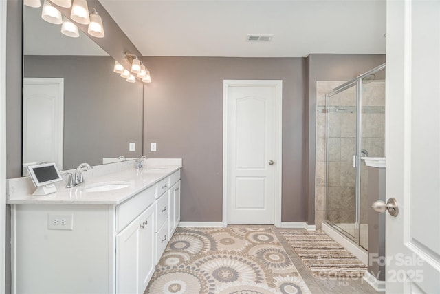 full bathroom featuring double vanity, a sink, visible vents, and a shower stall