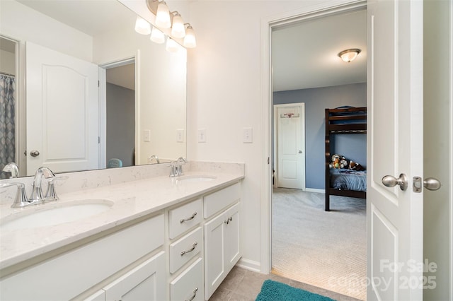 full bath with double vanity, tile patterned flooring, a sink, and baseboards