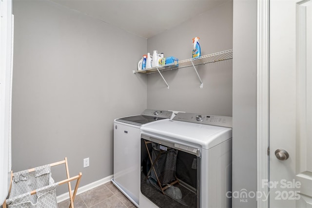 clothes washing area featuring laundry area, baseboards, washer and clothes dryer, and light tile patterned flooring