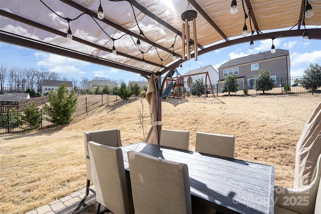 view of yard featuring a fenced backyard, playground community, and outdoor dining space