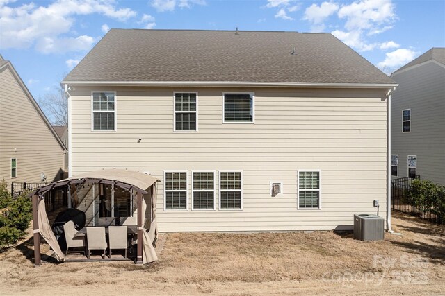 back of house with central air condition unit, a shingled roof, and fence