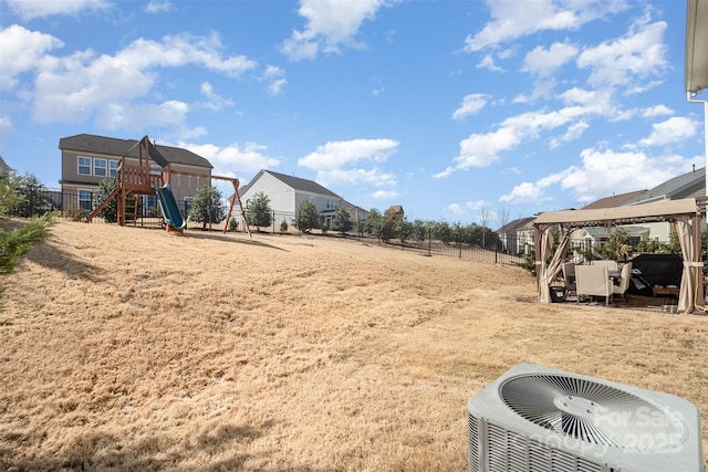 view of yard featuring central AC, a playground, and fence