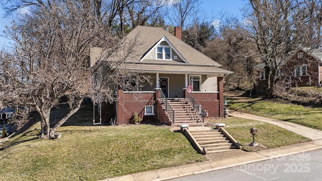 bungalow-style house featuring a chimney, stairway, a front yard, a porch, and brick siding