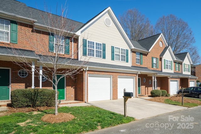 townhome / multi-family property featuring an attached garage, concrete driveway, and brick siding