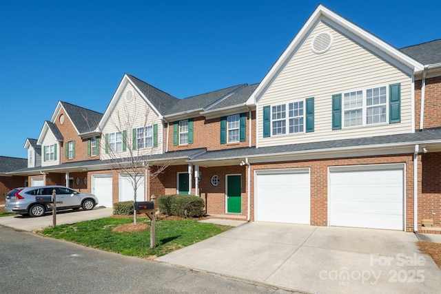 townhome / multi-family property with a garage, driveway, and brick siding