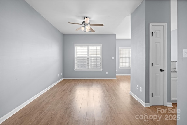 spare room featuring wood finished floors, a ceiling fan, and baseboards