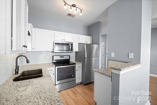 kitchen featuring light stone counters, a sink, visible vents, appliances with stainless steel finishes, and decorative backsplash