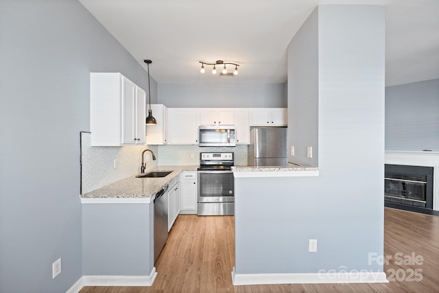 kitchen with appliances with stainless steel finishes, tasteful backsplash, a sink, and light stone countertops