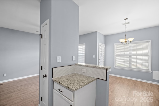 kitchen featuring decorative light fixtures, visible vents, white cabinetry, light stone countertops, and light wood-type flooring