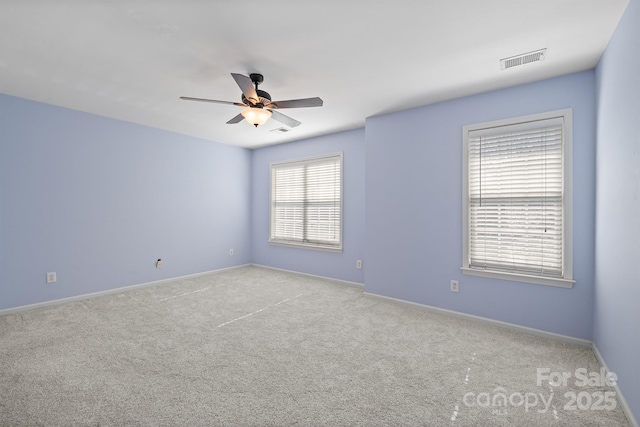 carpeted spare room featuring baseboards, visible vents, and a ceiling fan