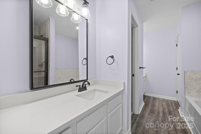 bathroom with baseboards, a bathtub, wood finished floors, and vanity