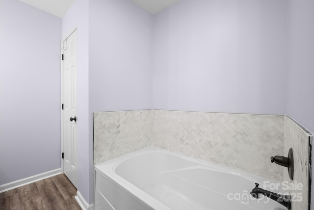 full bath with a garden tub, baseboards, and wood finished floors