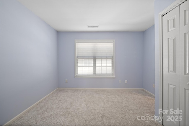 unfurnished room featuring carpet flooring, visible vents, and baseboards