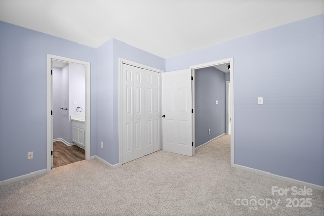 unfurnished bedroom with ensuite bathroom, carpet floors, a closet, and baseboards