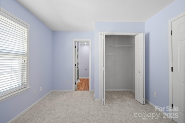 unfurnished bedroom featuring light carpet, a closet, and baseboards