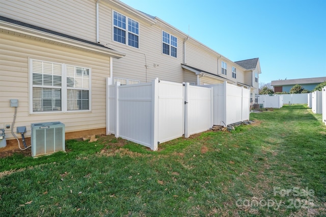 back of property featuring a fenced backyard, central AC unit, and a yard