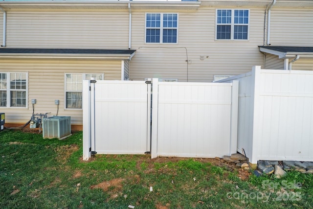 back of property with a yard, fence, and central AC unit