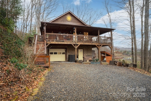 chalet / cabin featuring a garage and gravel driveway