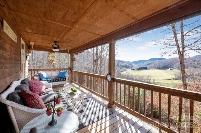 deck with an outdoor living space, a mountain view, and ceiling fan