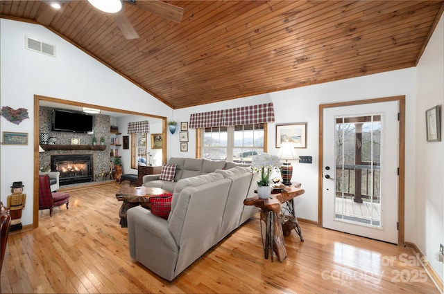 living area featuring visible vents, high vaulted ceiling, light wood-style flooring, a stone fireplace, and wood ceiling