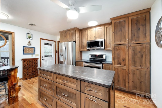 kitchen with visible vents, a center island, ceiling fan, light wood-type flooring, and appliances with stainless steel finishes