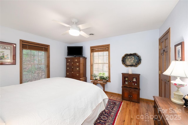 bedroom with a ceiling fan, light wood-style floors, visible vents, and baseboards