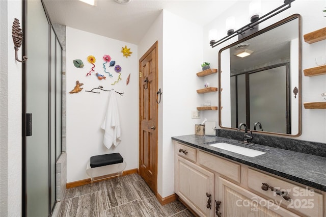 bathroom with vanity, baseboards, and a stall shower