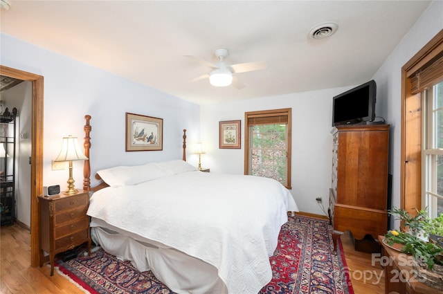 bedroom with light wood finished floors, visible vents, baseboards, and ceiling fan