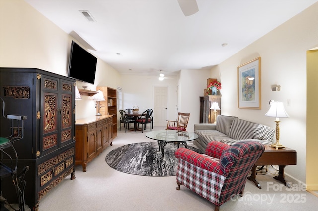 living area with visible vents, light colored carpet, and ceiling fan