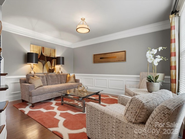 living area with a decorative wall, ornamental molding, wainscoting, and wood finished floors