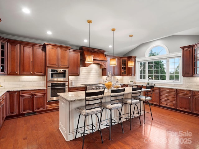 kitchen with glass insert cabinets, a kitchen breakfast bar, premium range hood, dark wood finished floors, and vaulted ceiling